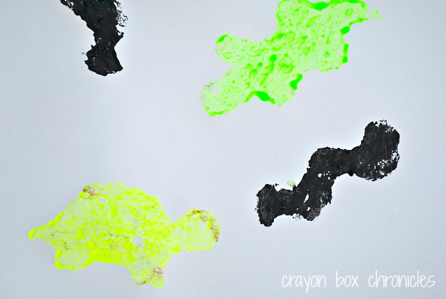 Prepare your paper, taping down the edges. Next, draw the letter R on your paper in glitter glue. While the R is drying, prepare reptile sponges.