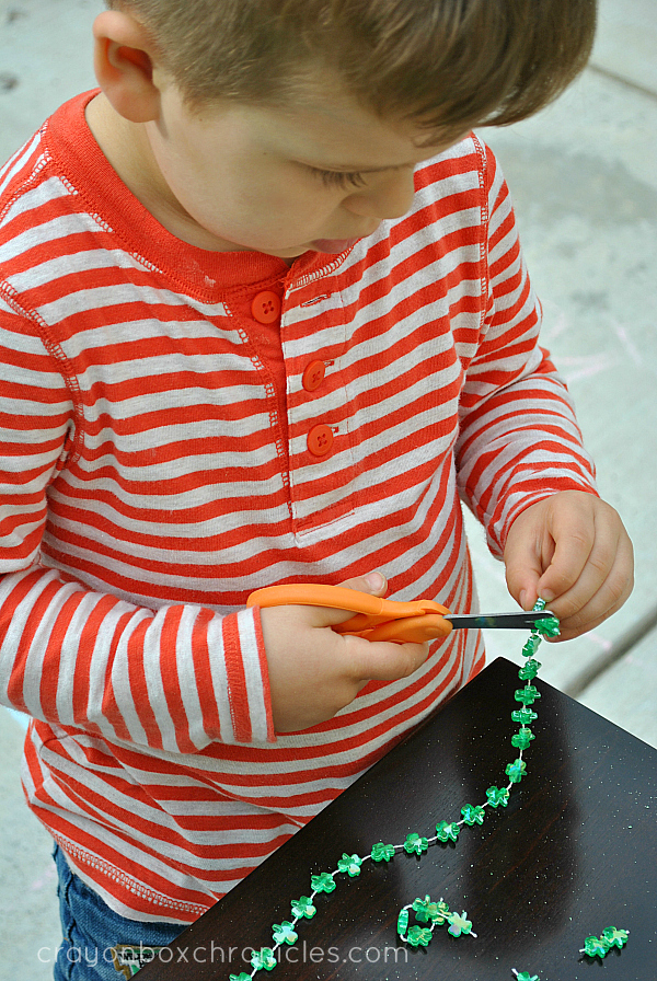 child cutting shamrock necklace