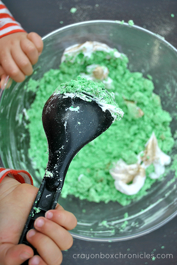 child stirring green foam dough